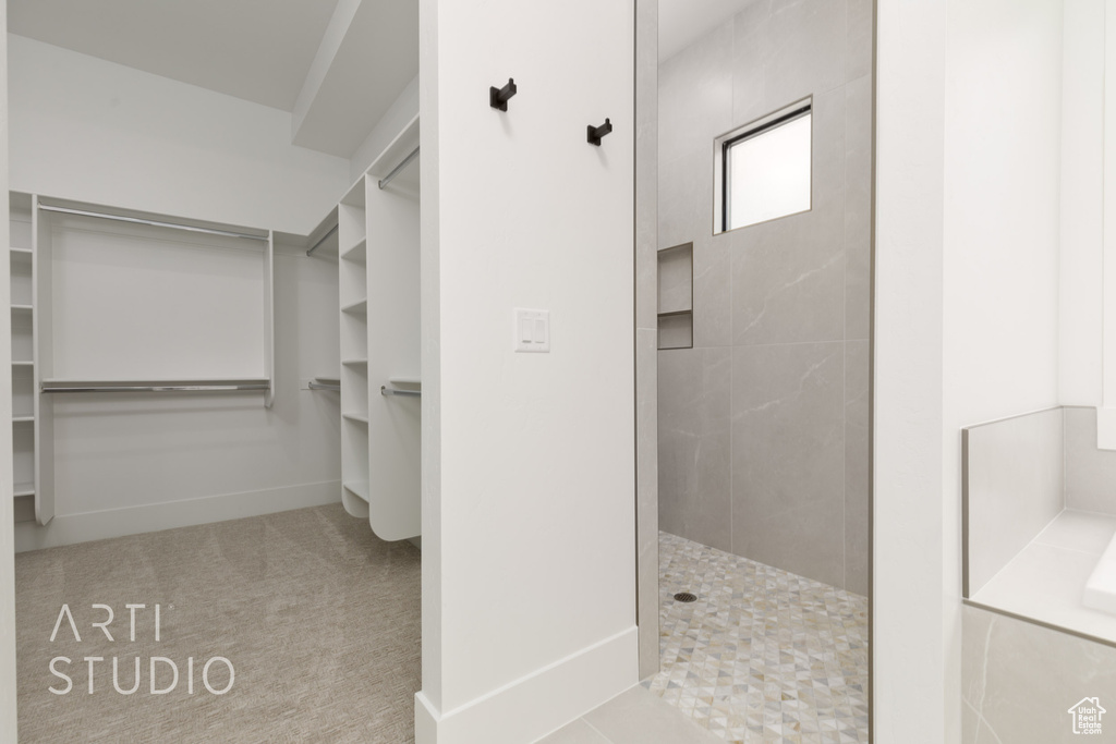 Bathroom featuring a walk in shower, a spacious closet, and baseboards