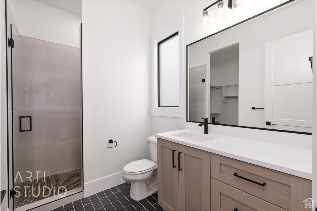 Full bathroom featuring a stall shower, toilet, tile patterned floors, and vanity