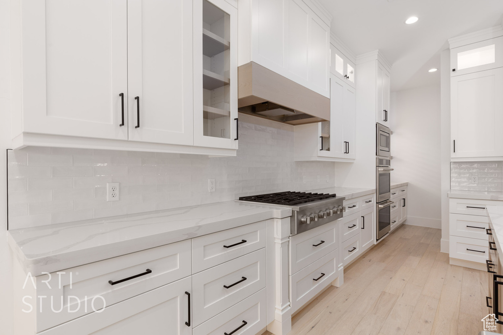 Kitchen featuring stainless steel appliances, white cabinets, light stone countertops, recessed lighting, and decorative backsplash
