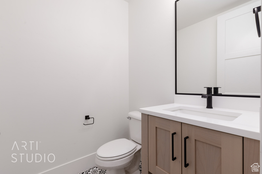 Bathroom with toilet, vanity, and baseboards