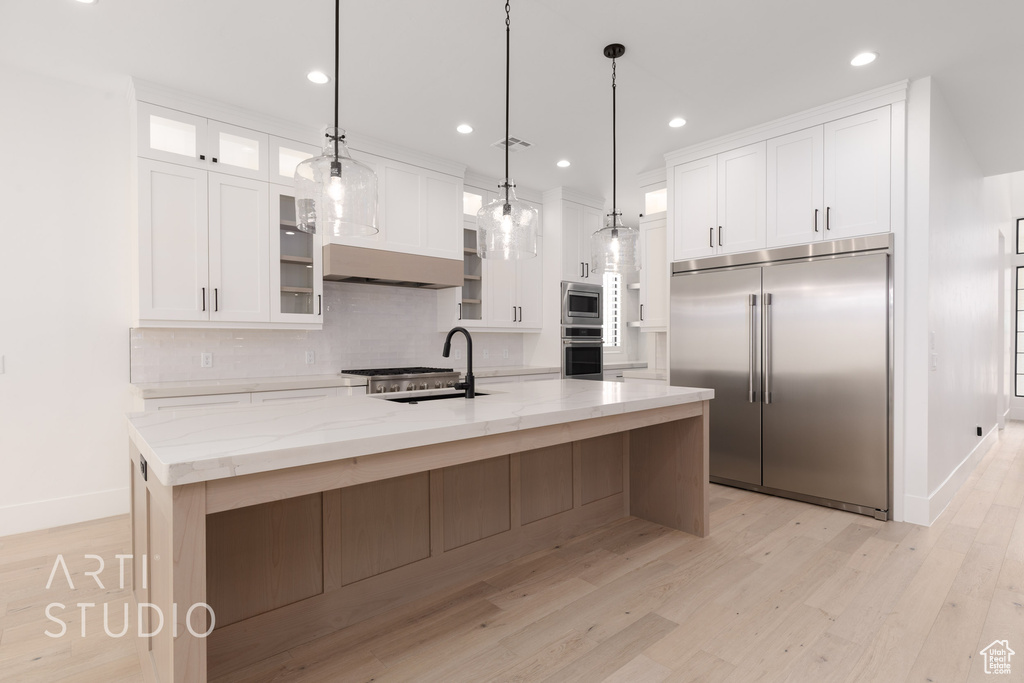 Kitchen with built in appliances, a sink, white cabinets, and recessed lighting