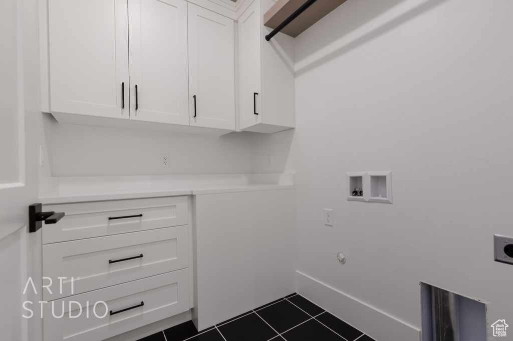Clothes washing area featuring electric dryer hookup, cabinet space, dark tile patterned floors, hookup for a washing machine, and baseboards
