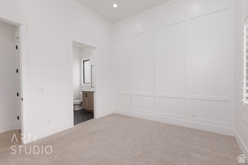 Unfurnished bedroom featuring carpet floors, connected bathroom, a decorative wall, and recessed lighting