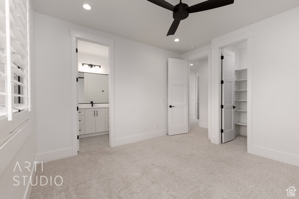 Unfurnished bedroom with light colored carpet, recessed lighting, baseboards, a spacious closet, and ensuite bathroom