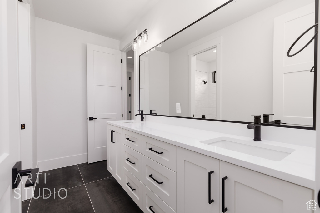 Bathroom with double vanity, tile patterned flooring, and baseboards