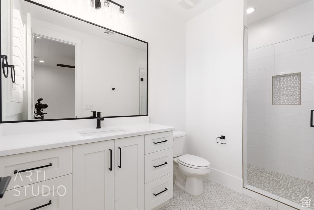 Full bathroom featuring toilet, tiled shower, and vanity