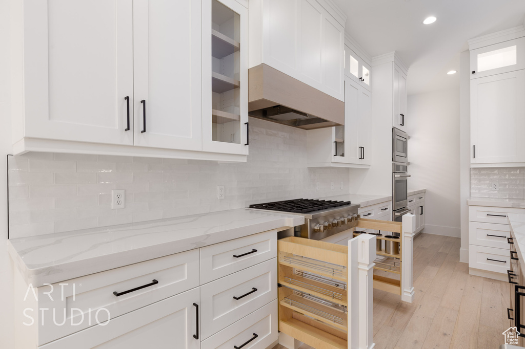 Kitchen featuring white cabinetry, decorative backsplash, stainless steel appliances, light stone counters, and recessed lighting