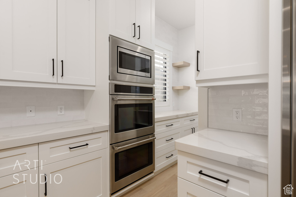 Kitchen featuring stainless steel appliances, tasteful backsplash, and white cabinets