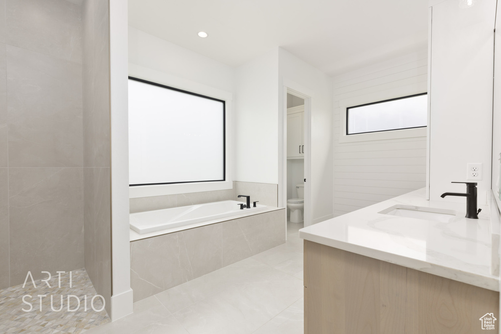Bathroom with toilet, a bath, double vanity, and tile patterned floors