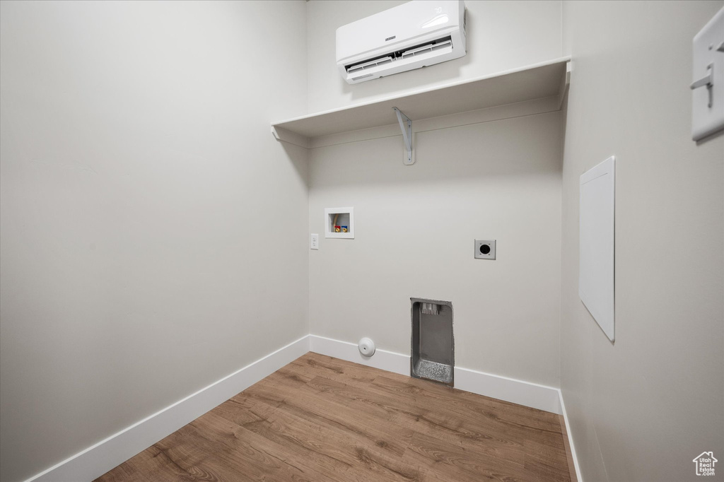 Laundry area with a wall mounted air conditioner, washer hookup, wood finished floors, baseboards, and hookup for an electric dryer