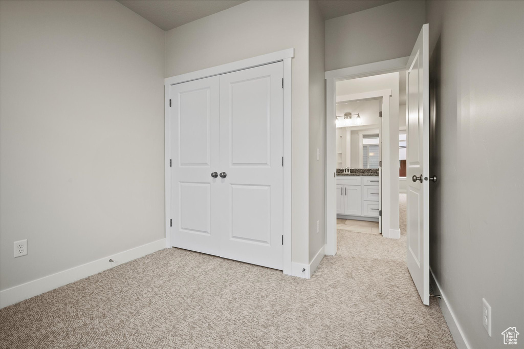 Unfurnished bedroom with light colored carpet, baseboards, and a closet