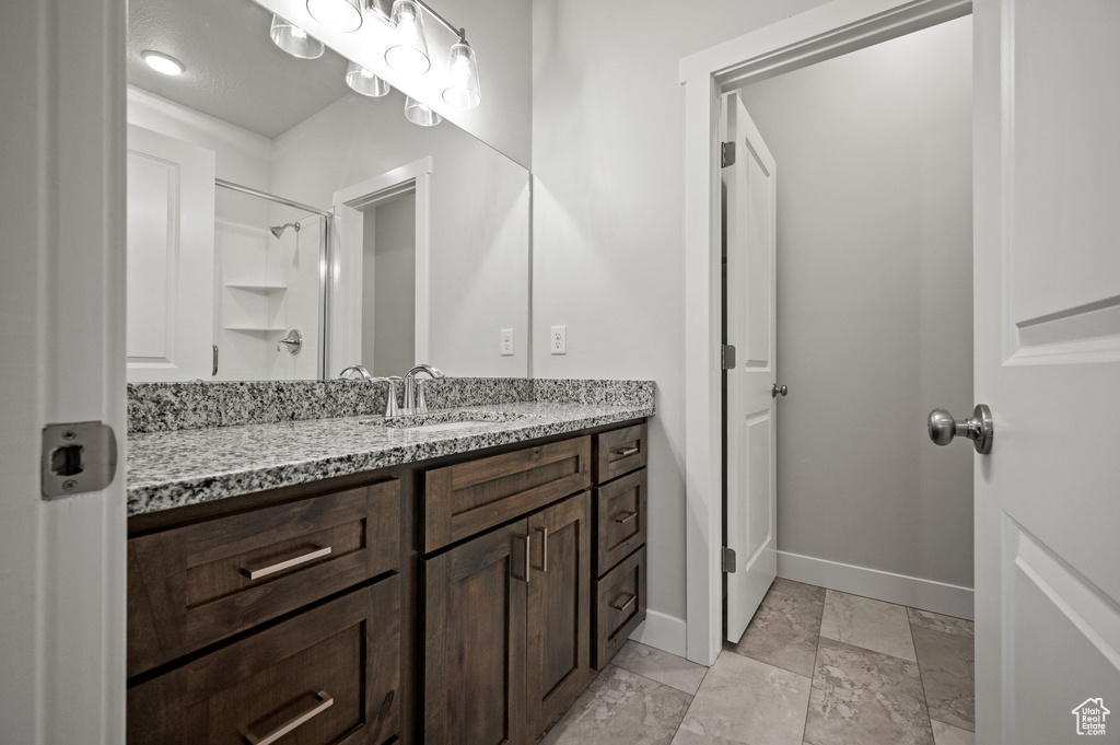 Bathroom featuring baseboards, vanity, and a shower