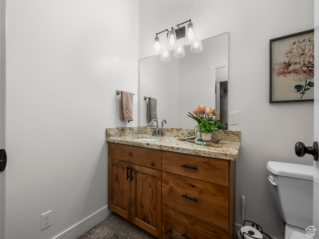 Bathroom with vanity, toilet, and baseboards