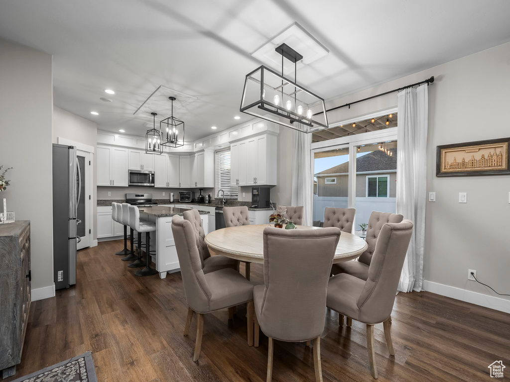 Dining room featuring a chandelier, dark wood-type flooring, baseboards, and recessed lighting
