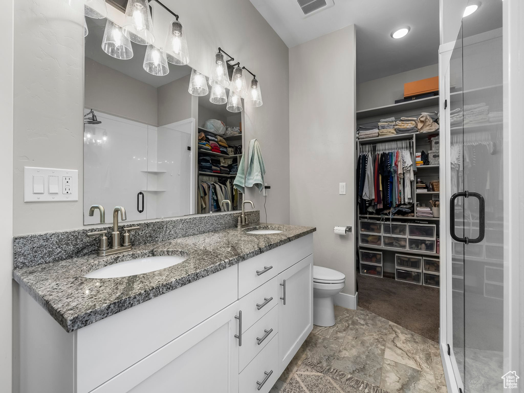 Bathroom with a shower stall, double vanity, a spacious closet, and toilet