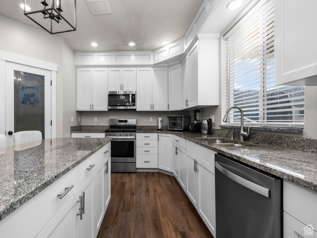 Kitchen featuring stainless steel appliances, a sink, recessed lighting, dark wood finished floors, and white cabinetry