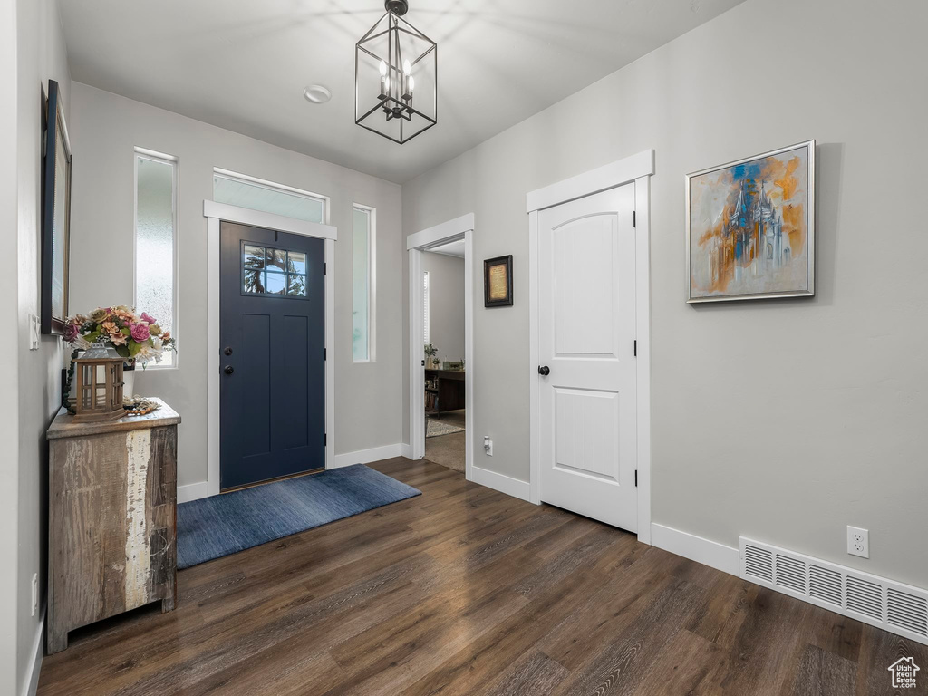 Foyer featuring dark wood finished floors, a chandelier, and baseboards