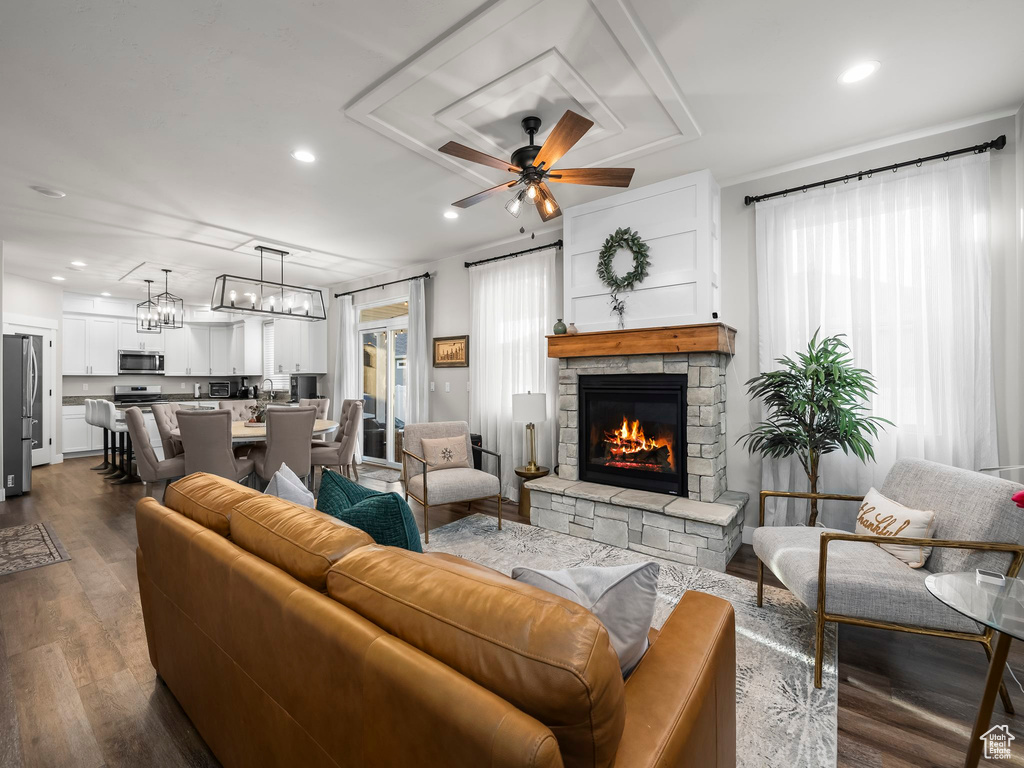 Living room with healthy amount of natural light, a fireplace, dark wood-style floors, recessed lighting, and a ceiling fan