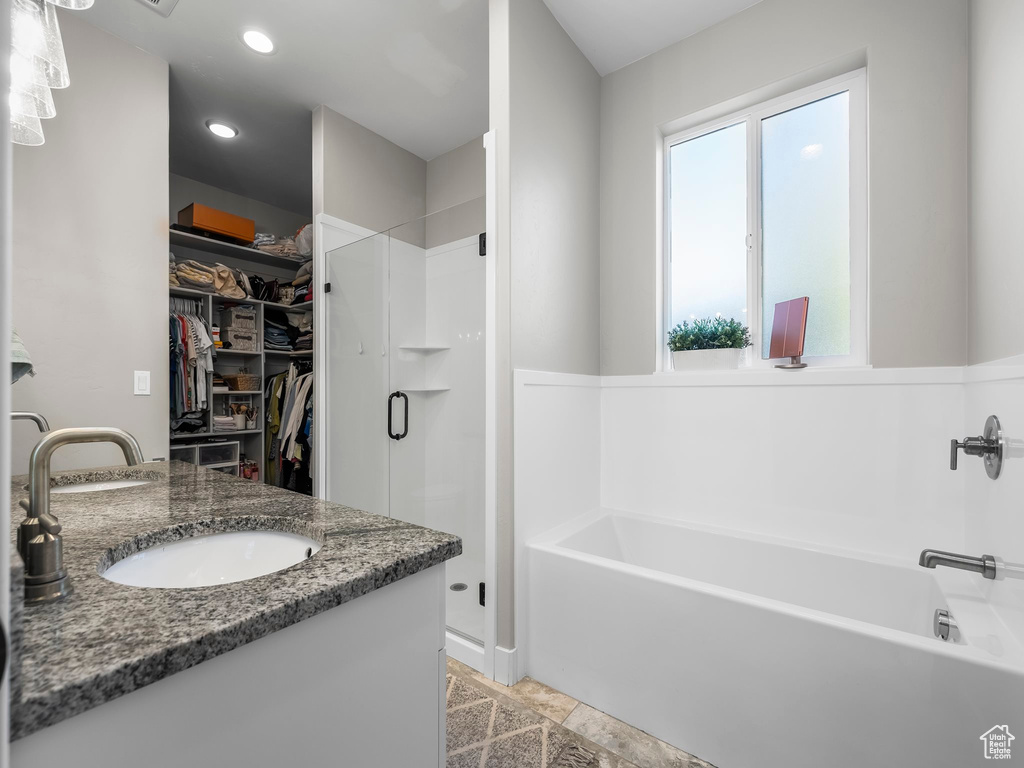 Full bath with a shower stall, a spacious closet, a bath, vanity, and recessed lighting