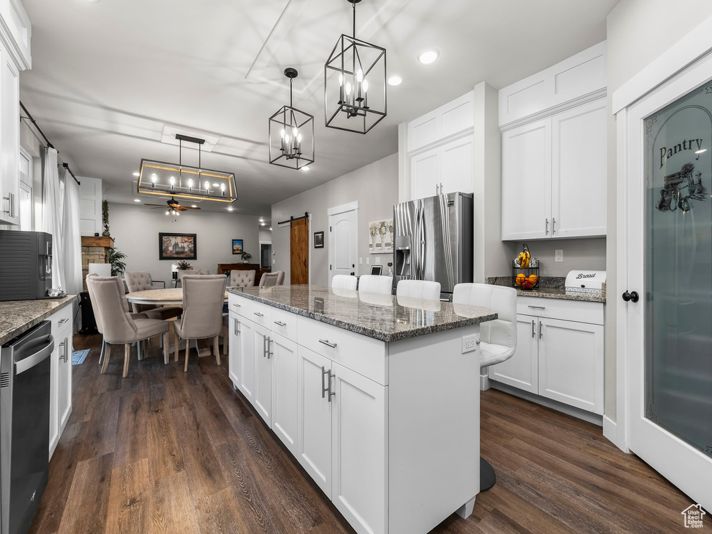 Kitchen with appliances with stainless steel finishes, a kitchen island, a chandelier, dark wood-style flooring, and recessed lighting