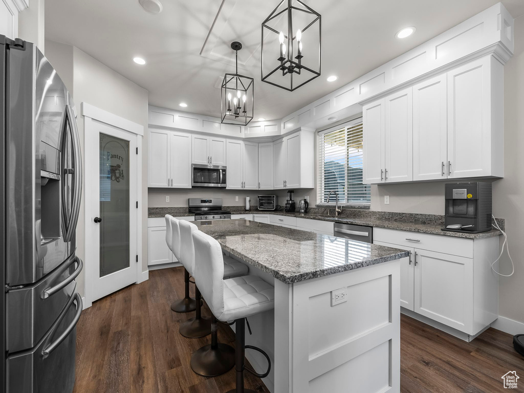 Kitchen featuring appliances with stainless steel finishes, dark wood finished floors, a chandelier, a center island, and recessed lighting