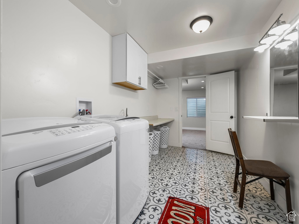 Clothes washing area with cabinet space, separate washer and dryer, baseboards, and light flooring