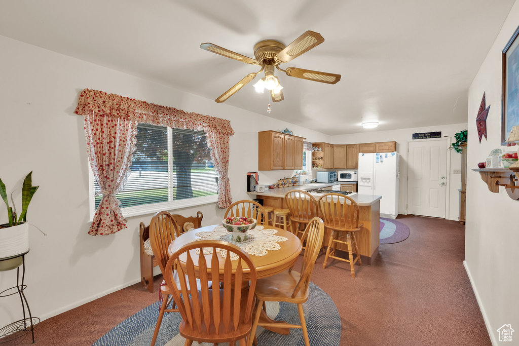 Dining area featuring a ceiling fan, dark colored carpet, and baseboards