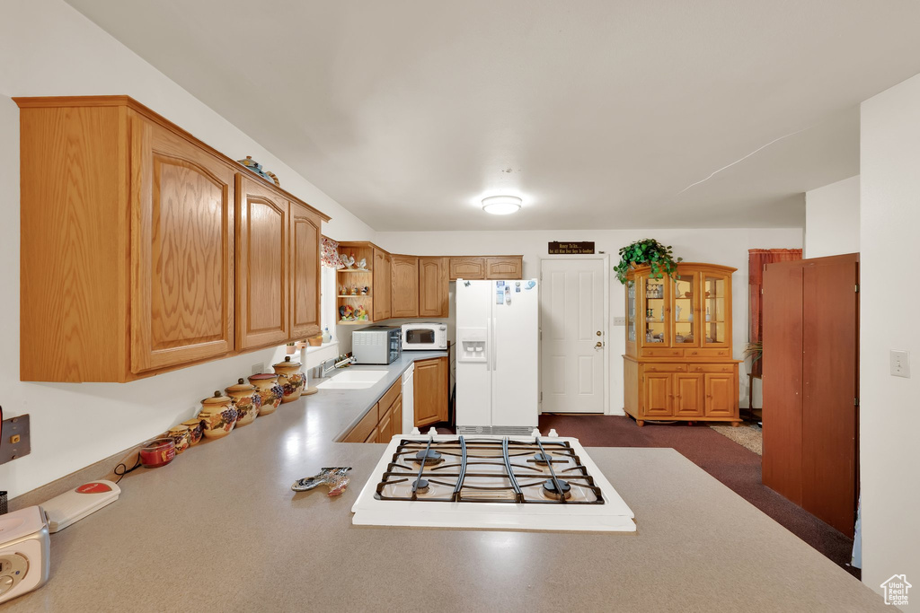 Kitchen with white appliances, open shelves, a sink, and light countertops