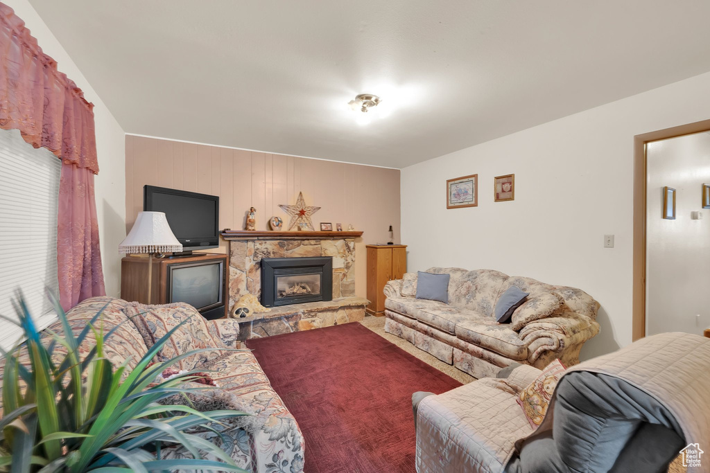 Living room featuring a stone fireplace and carpet flooring