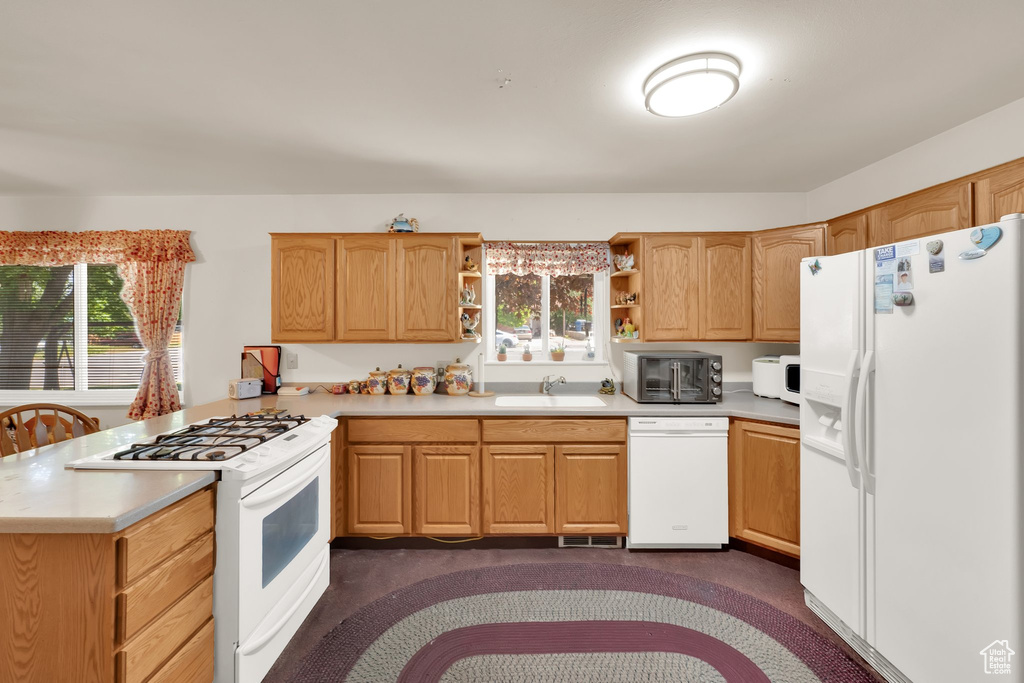 Kitchen featuring white appliances, a sink, a peninsula, open shelves, and plenty of natural light
