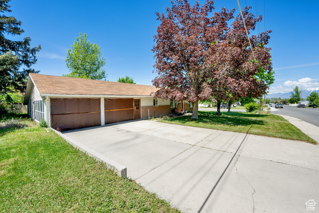 View of front of home featuring a front yard, driveway, roof with shingles, and a garage