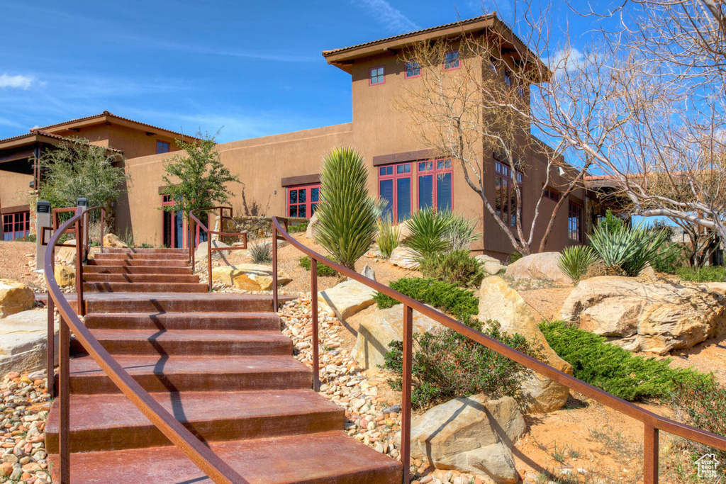 View of front facade featuring stucco siding and stairs