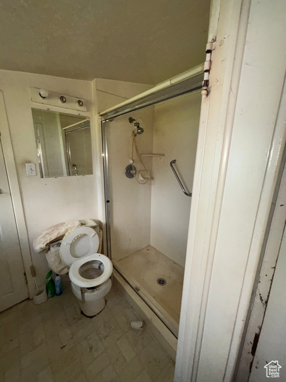Bathroom with a stall shower, tile patterned floors, and toilet