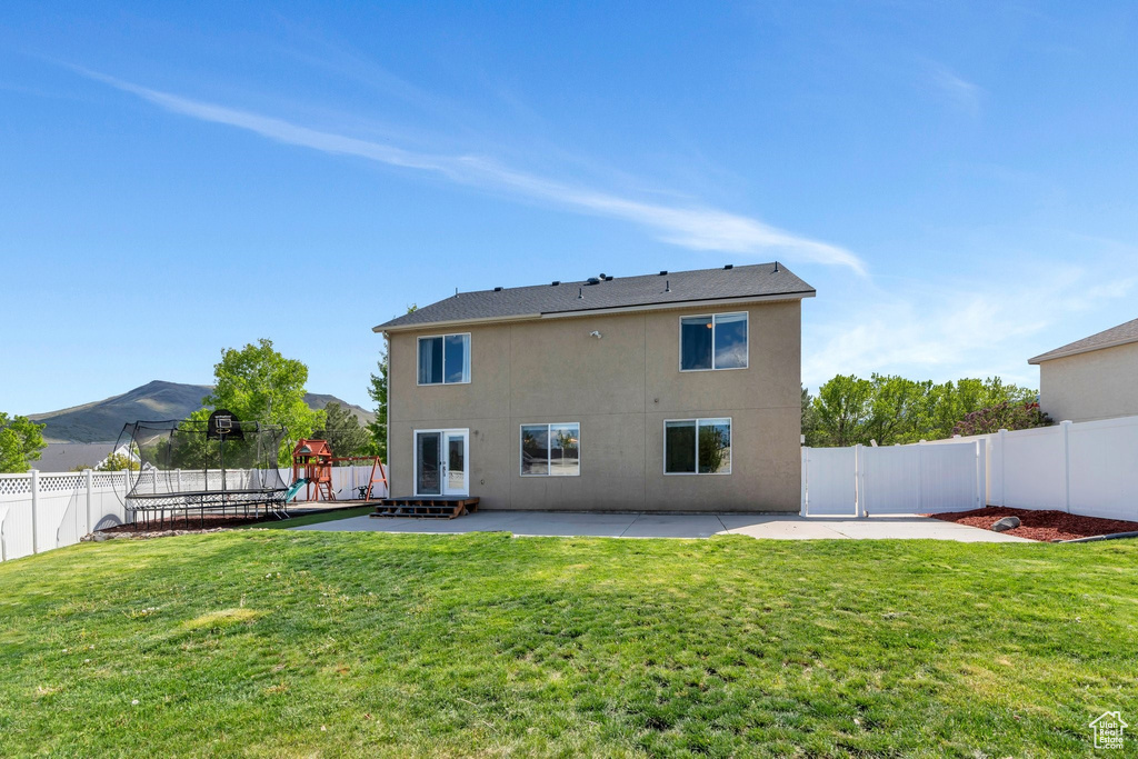 Rear view of house with a patio, a playground, stucco siding, and a trampoline