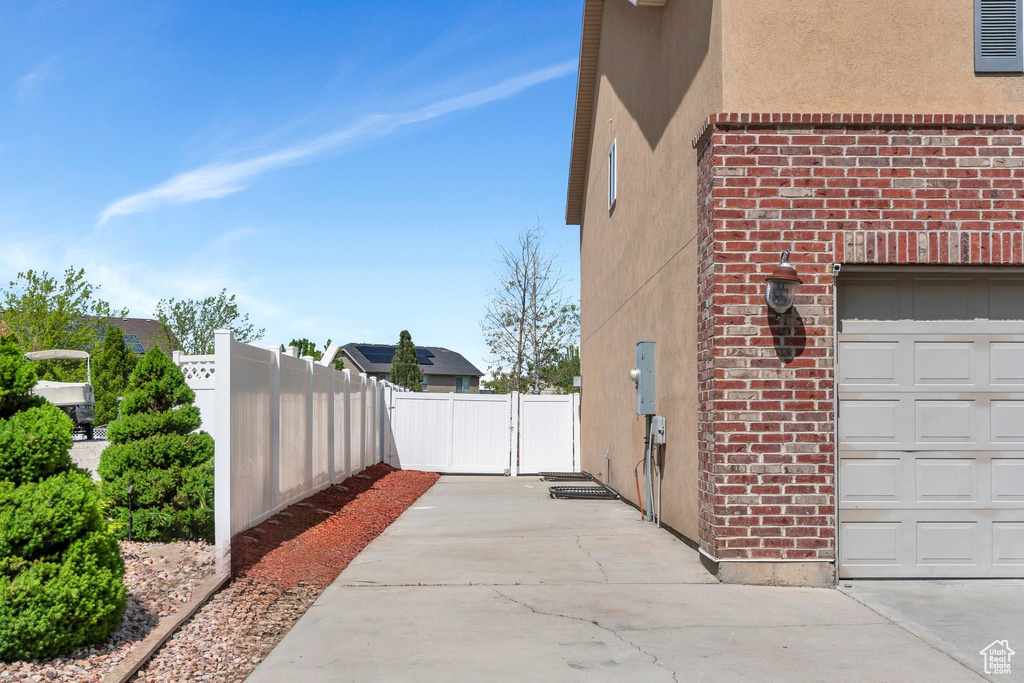 View of side of property featuring fence, brick siding, stucco siding, and a garage