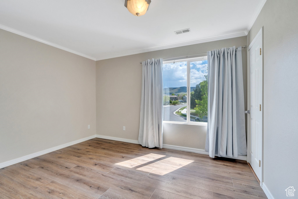 Spare room featuring crown molding, wood finished floors, and baseboards