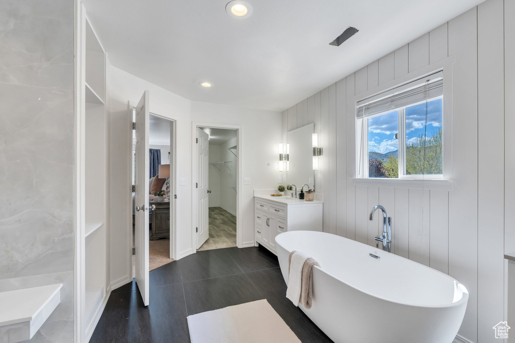 Full bathroom featuring a soaking tub, vanity, a spacious closet, and recessed lighting