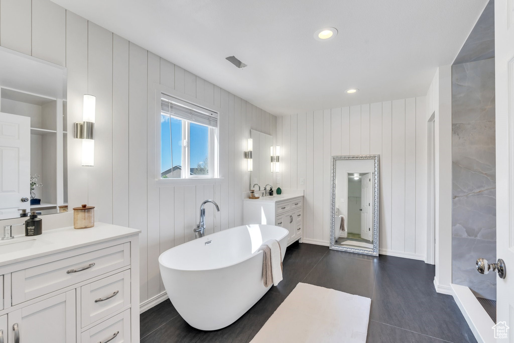 Bathroom with a soaking tub, vanity, and recessed lighting