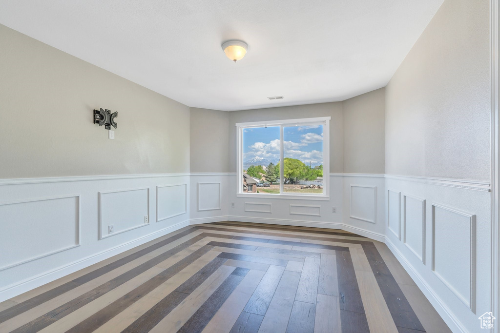Spare room with a wainscoted wall and dark wood-type flooring