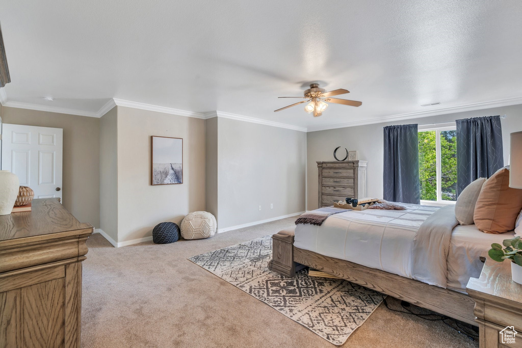 Carpeted bedroom featuring baseboards, ornamental molding, and a ceiling fan