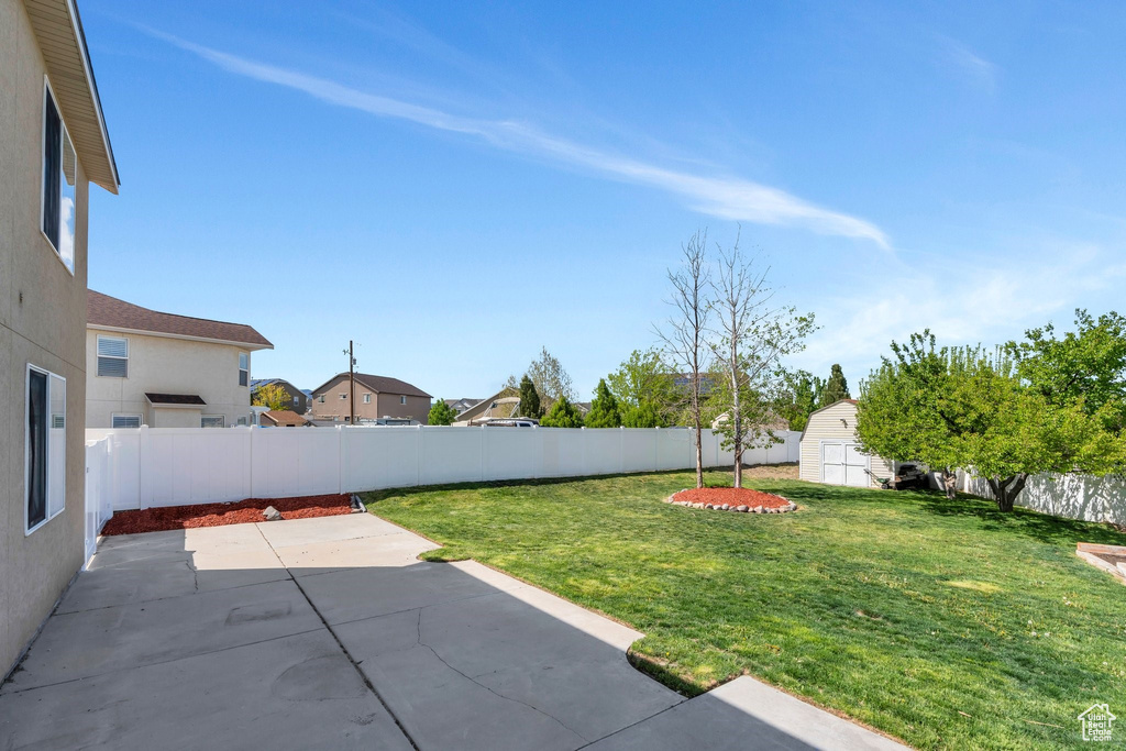 View of yard featuring a patio, a storage unit, an outbuilding, and a residential view