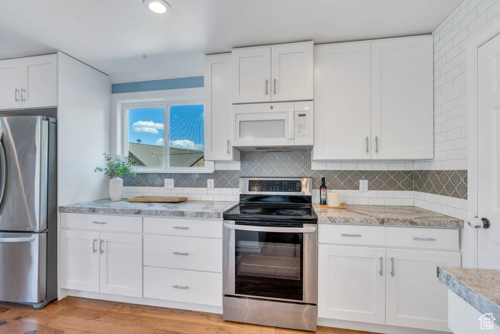 Kitchen with stainless steel appliances, white cabinetry, and tasteful backsplash