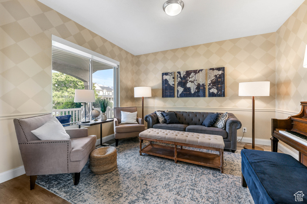 Living room featuring wallpapered walls, baseboards, and wood finished floors