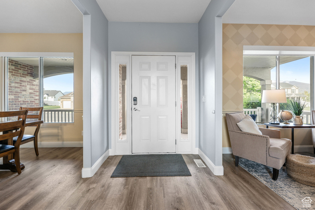 Foyer with wood finished floors, baseboards, plenty of natural light, and wallpapered walls
