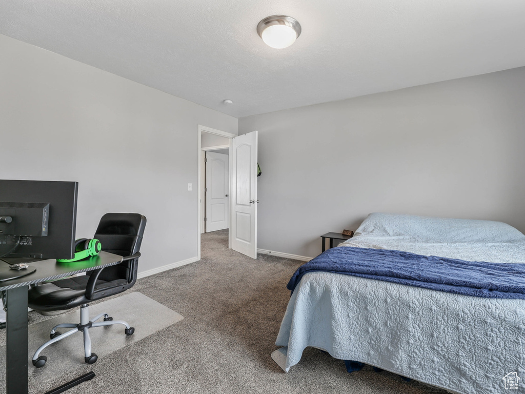 Carpeted bedroom with an office area and baseboards
