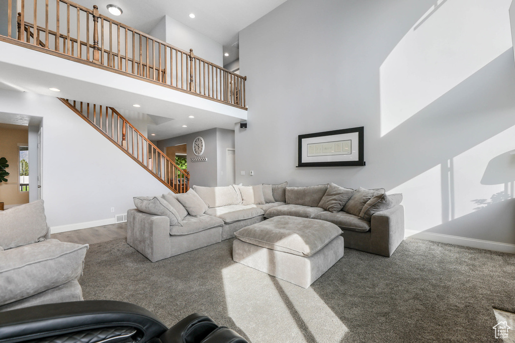 Carpeted living room with a towering ceiling, recessed lighting, stairway, and baseboards