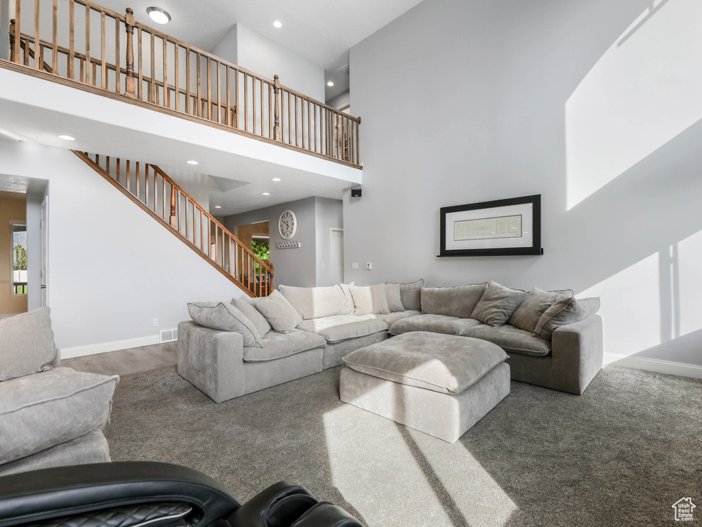 Carpeted living room with a towering ceiling, recessed lighting, stairway, and baseboards