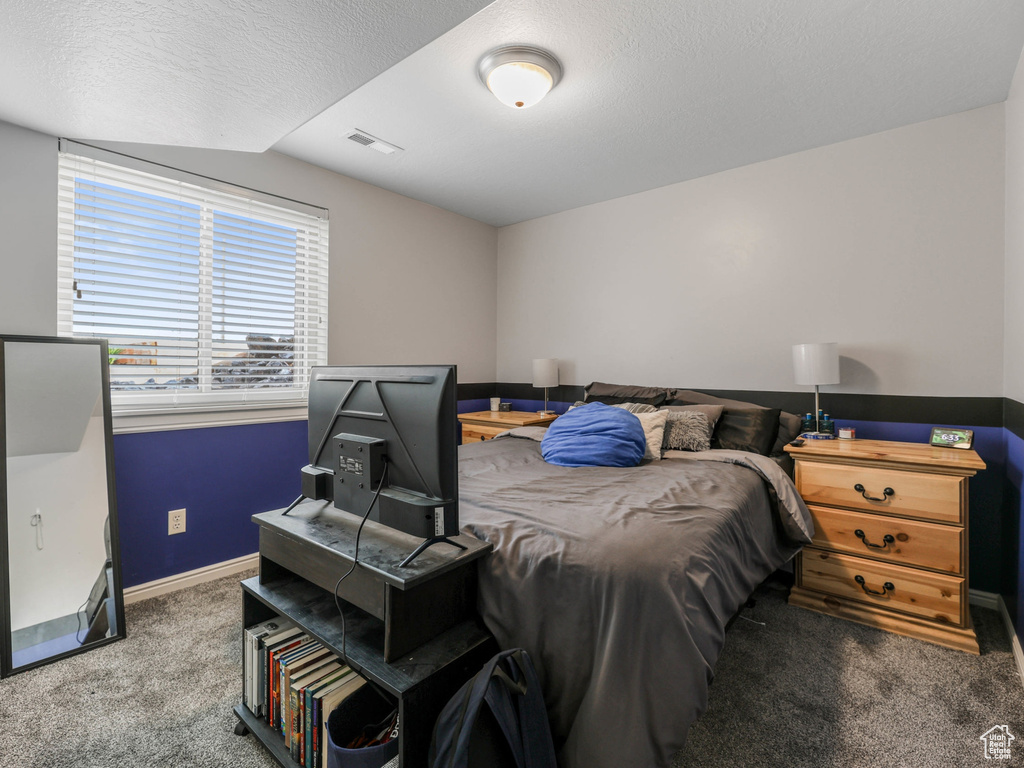 Bedroom with carpet floors, baseboards, and a textured ceiling