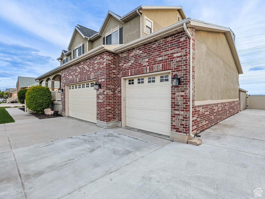 View of home\\\'s exterior with concrete driveway, a gate, stucco siding, brick siding, and fence