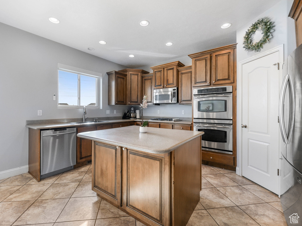 Kitchen with appliances with stainless steel finishes, a sink, a kitchen island, recessed lighting, and light tile patterned flooring